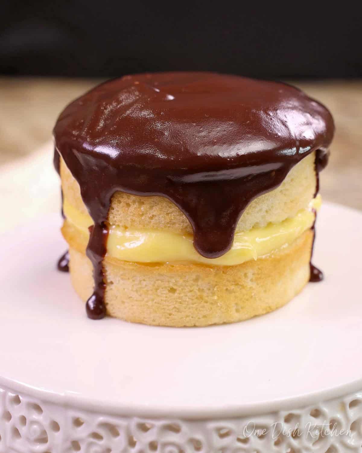a mini boston cream pie on a white cake stand.
