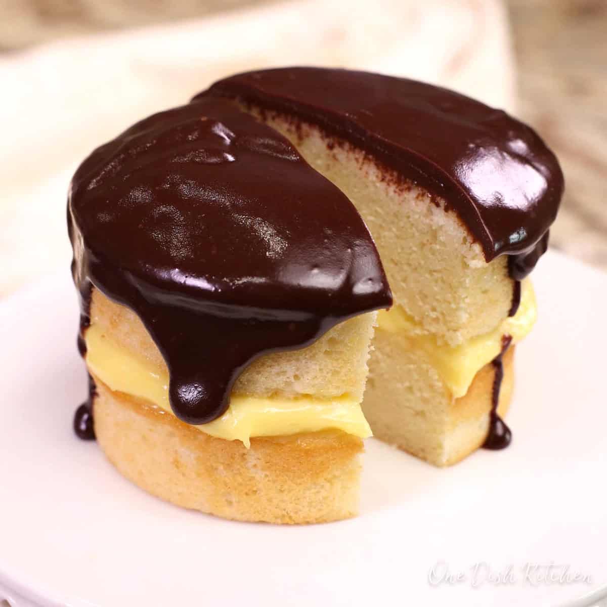 a boston cream pie on a cake stand. The cake is cut in half.