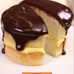 a small boston cream pie sliced in half on a cake plate.