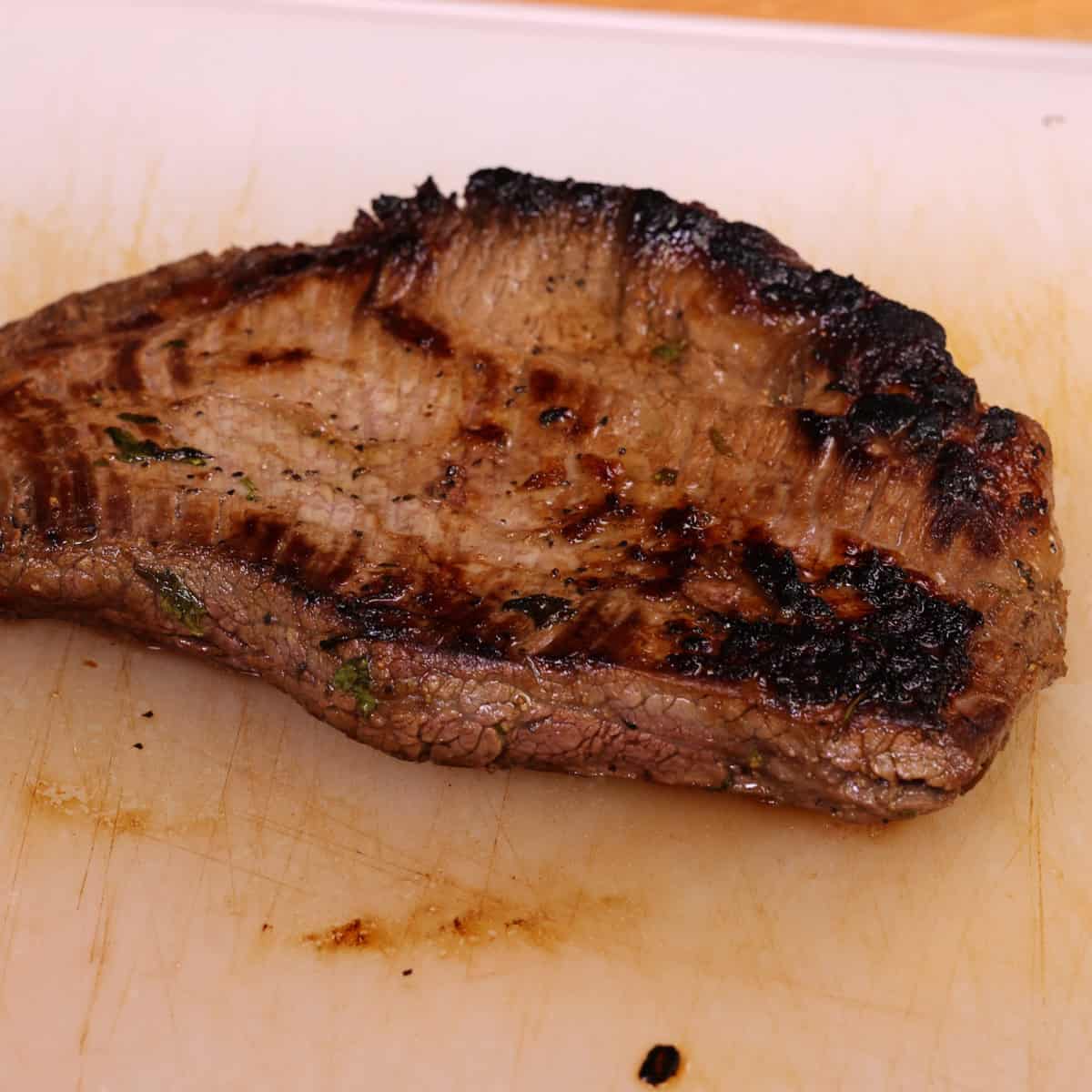 a flank steak resting on a cutting board.