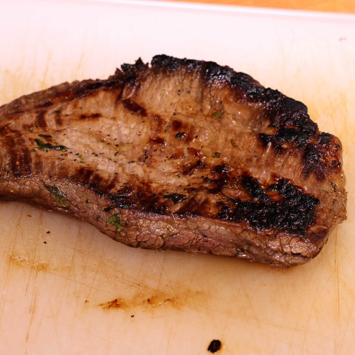 a flank steak resting on a cutting board.