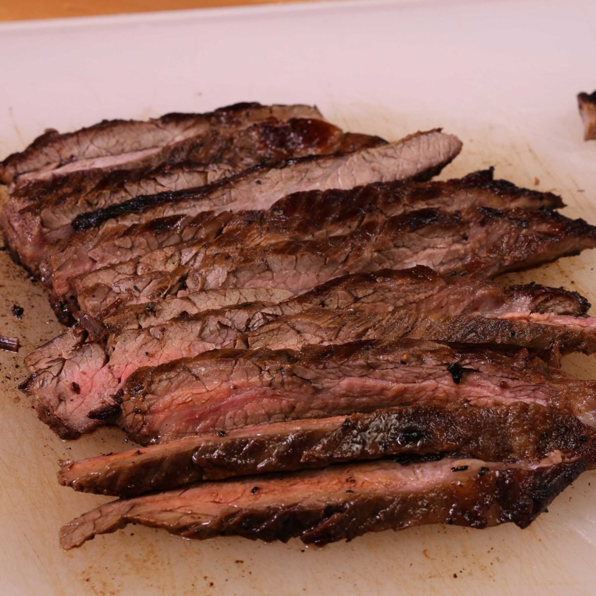 flank steak cooked and thinly sliced on a cutting board.