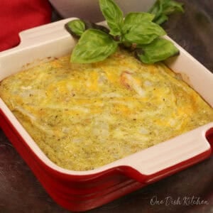 a small crustless tomato quiche with pesto in a small baking dish with fresh basil.