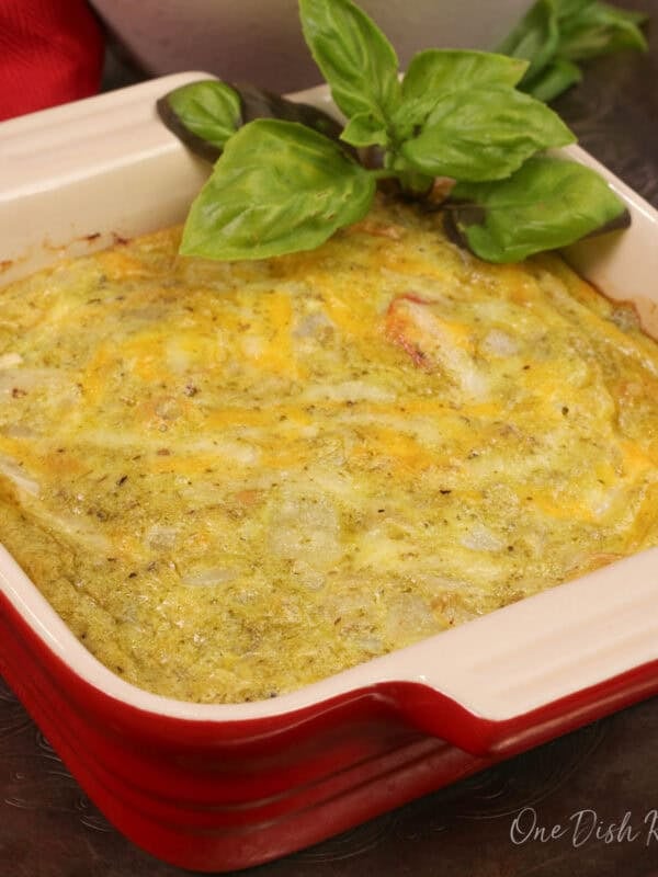 a small crustless tomato quiche with pesto in a small baking dish with fresh basil.