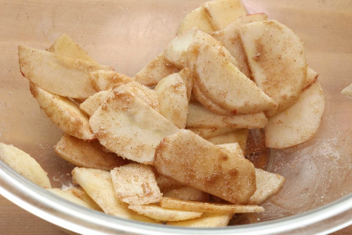 apple slices mixed with sugar and spices in a large mixing bowl.