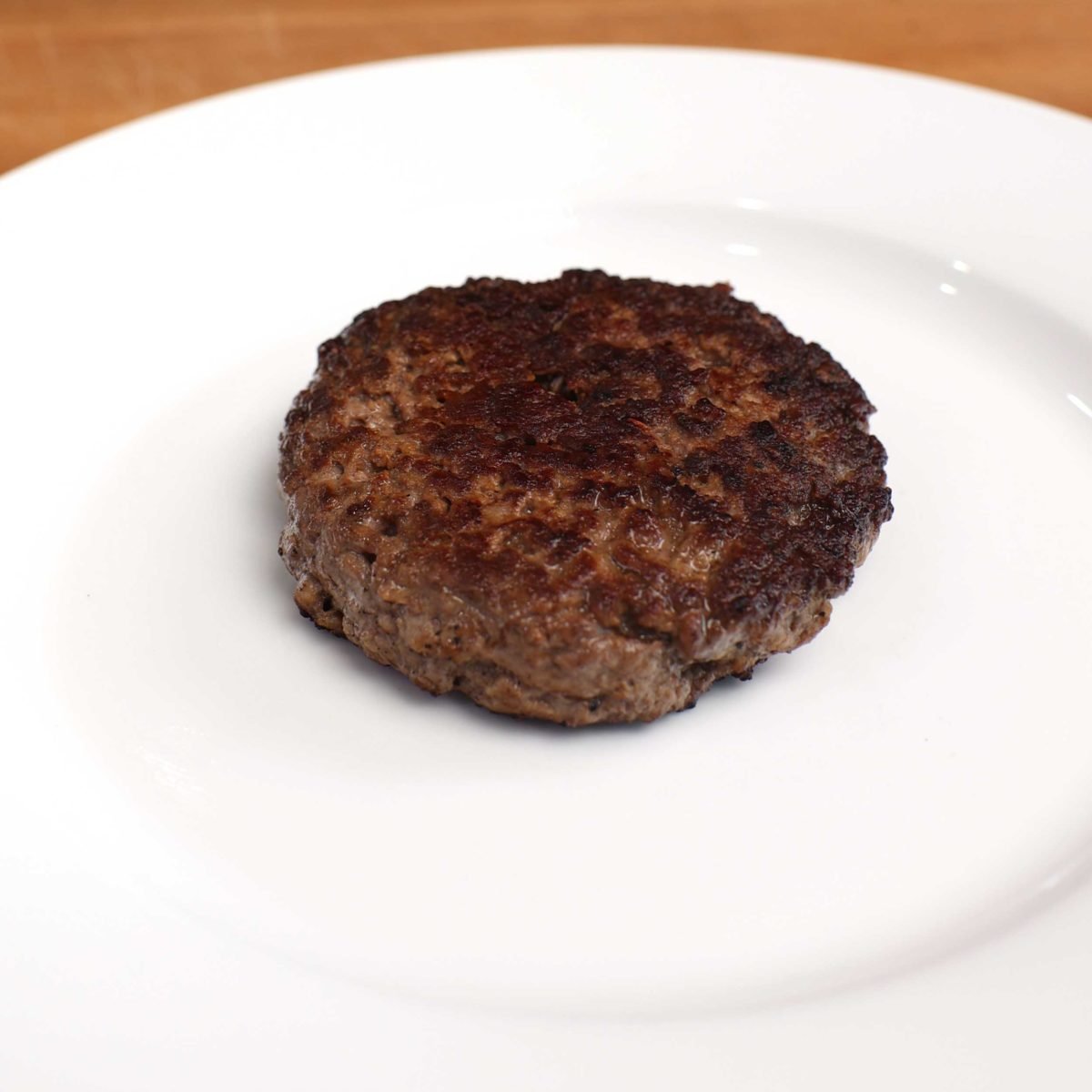 a cooked hamburger patty on a white plate.