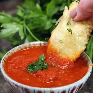 A single parmesan chicken tender dipped in marinara sauce.