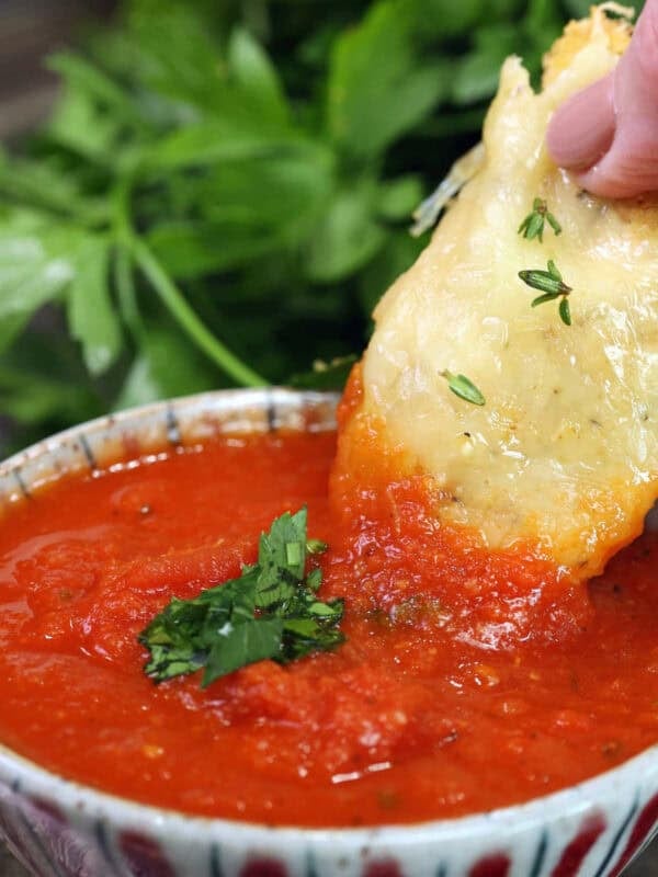 A single parmesan chicken tender dipped in marinara sauce.