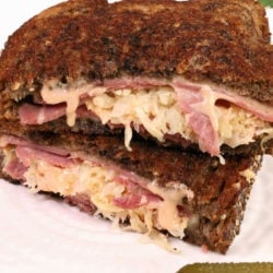 Two halves of a Reuben sandwich showing corned beef and sauerkraut oozing out the end