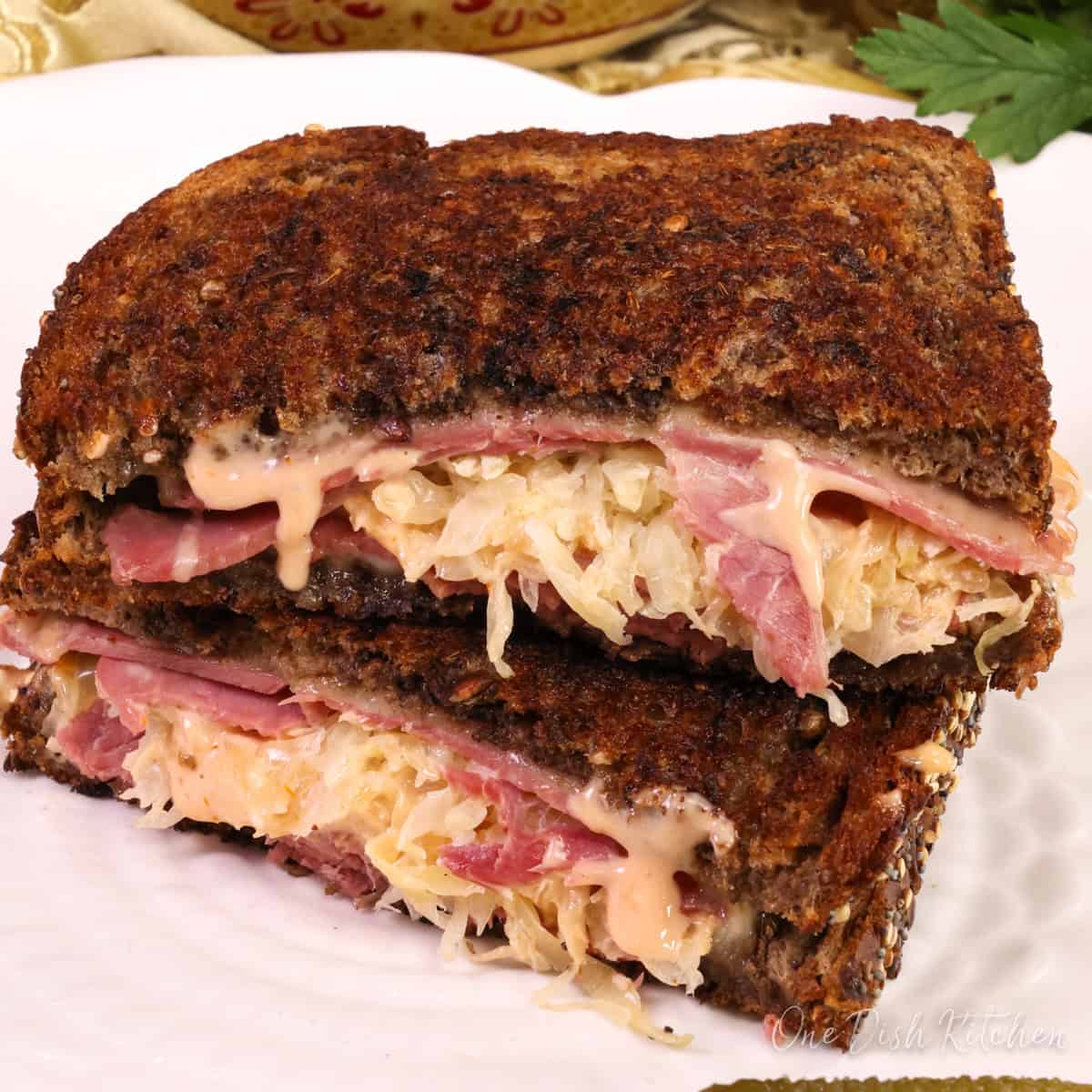 a reuben sandwich made with corned beef and swiss cheese on a white plate.