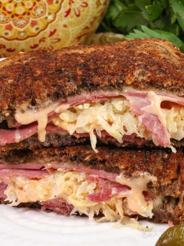 a reuben sandwich made with corned beef and swiss cheese on a white plate.