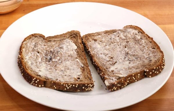 two slices of buttered rye bread on a white plate