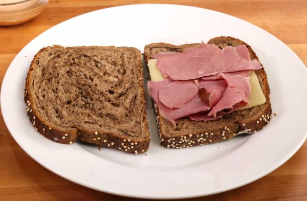 corned beef and swiss cheese on one slice of rye bread on a white plate