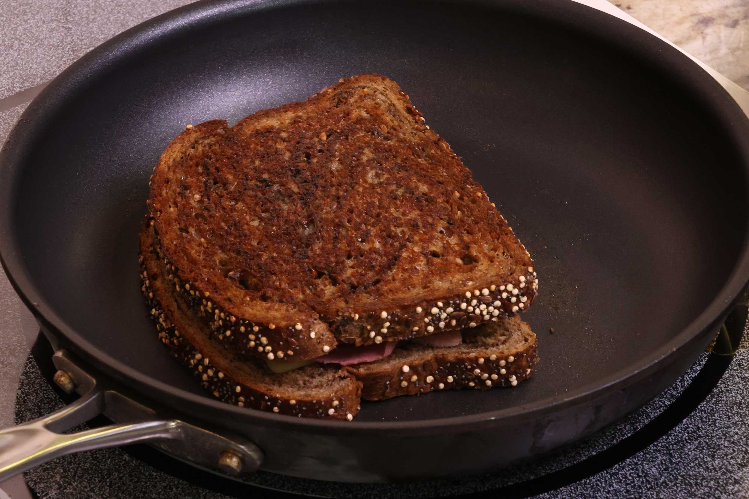 pan-grilling a reuben sandwich on a non stick skillet on the stove.