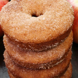 four apple cider doughnuts stacked on top of one another