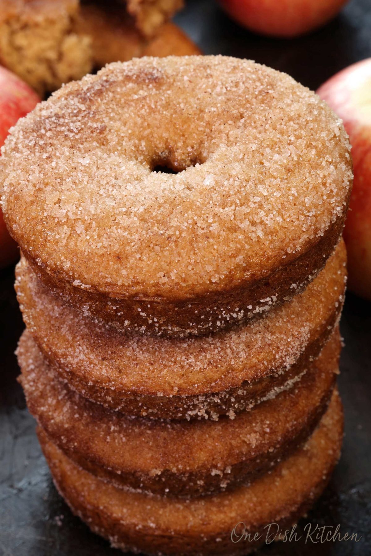 four apple cider doughnuts stacked on top of one another.