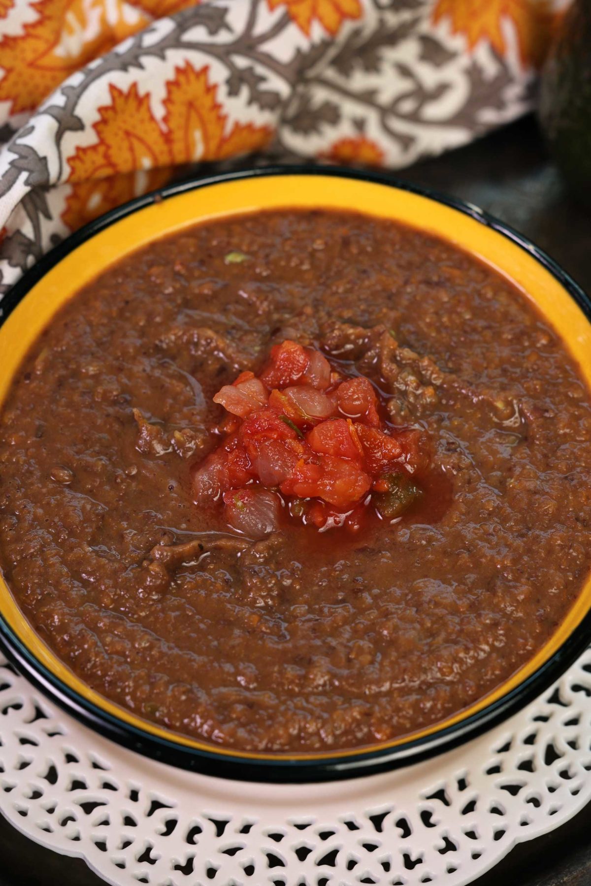 an overhead view of black bean soup with a dollop of salsa in the center of the bowl.