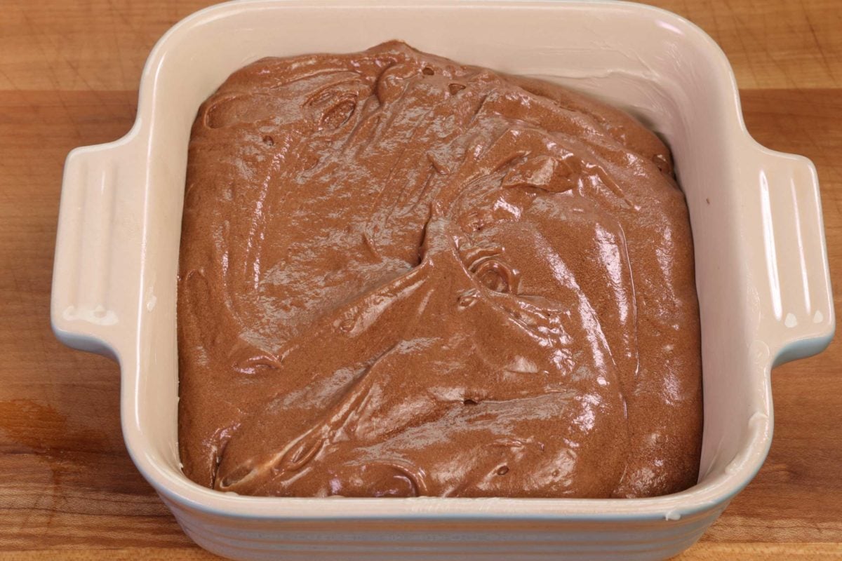 chocolate cake batter in a small square blue baking dish.