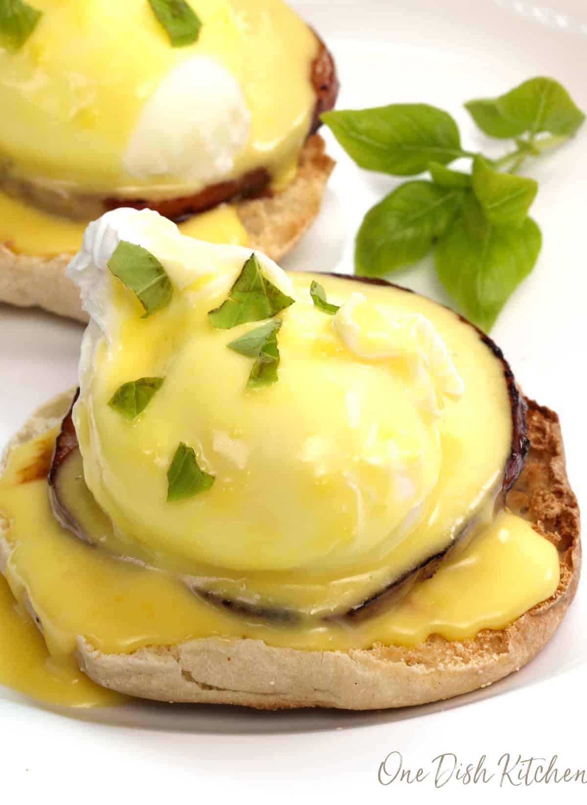 eggs benedict with hollandaise sauce on a white plate.