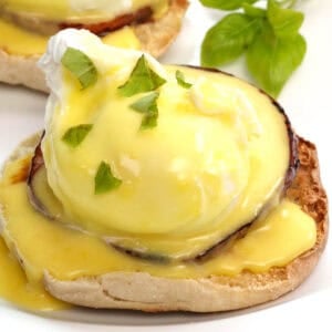 eggs benedict with hollandaise sauce on a white plate.