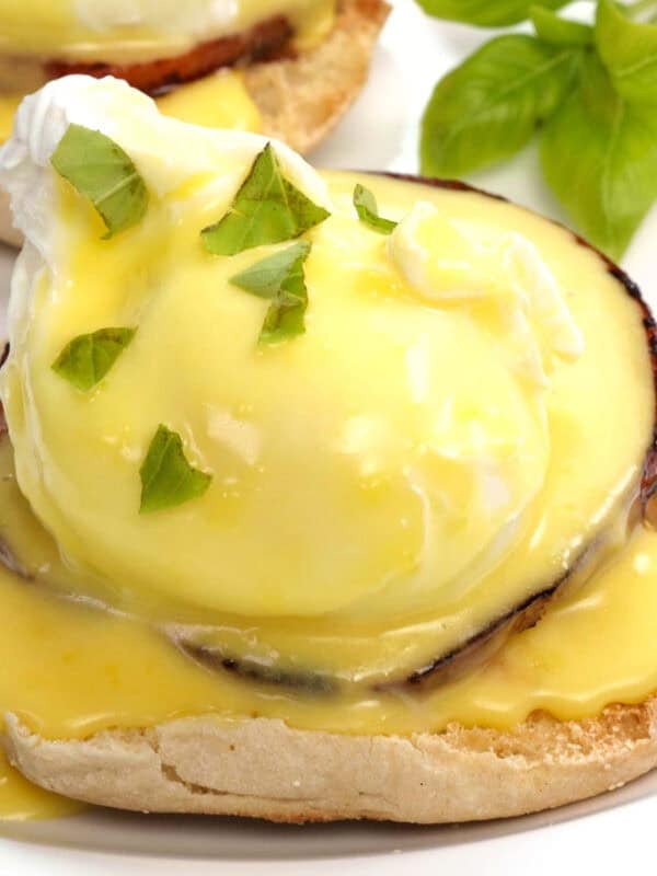 eggs benedict with hollandaise sauce on a white plate.