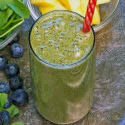 a green smoothie in a glass with a red straw,