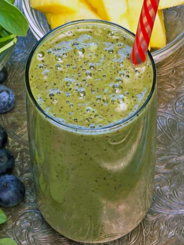a green smoothie in a glass with a red straw,