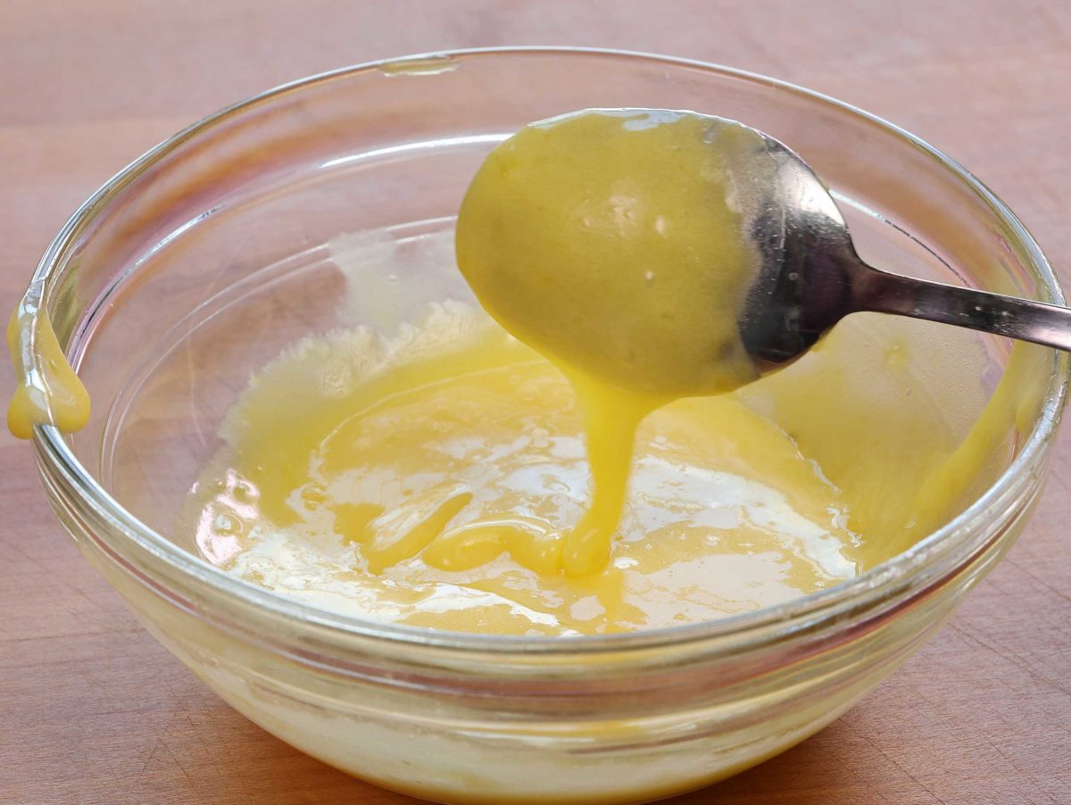 a small bowl of hollandaise sauce with a spoon over the top of the bowl.
