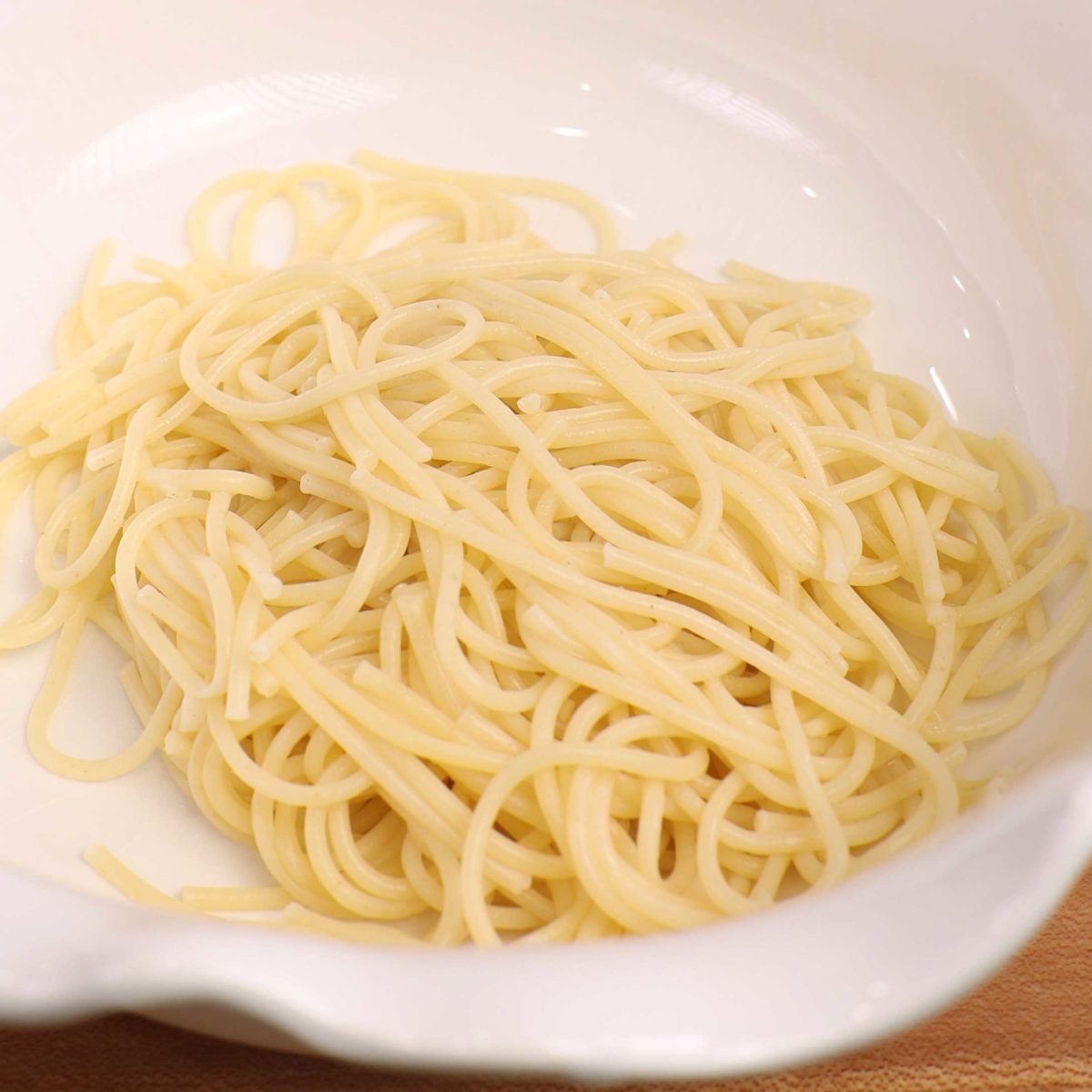 cooked spaghetti in a white bowl.