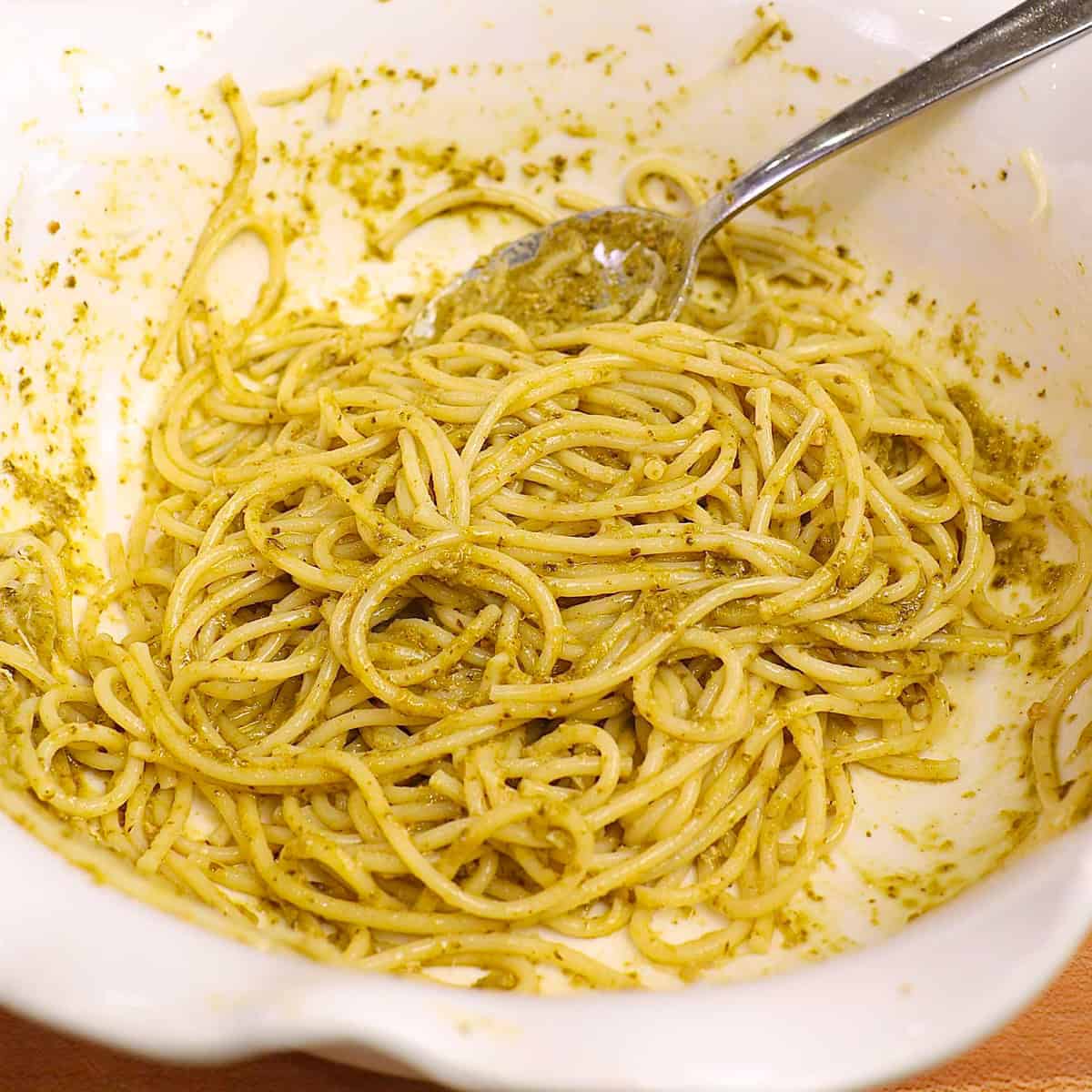 a single serving of pesto pasta in a mixing bowl.