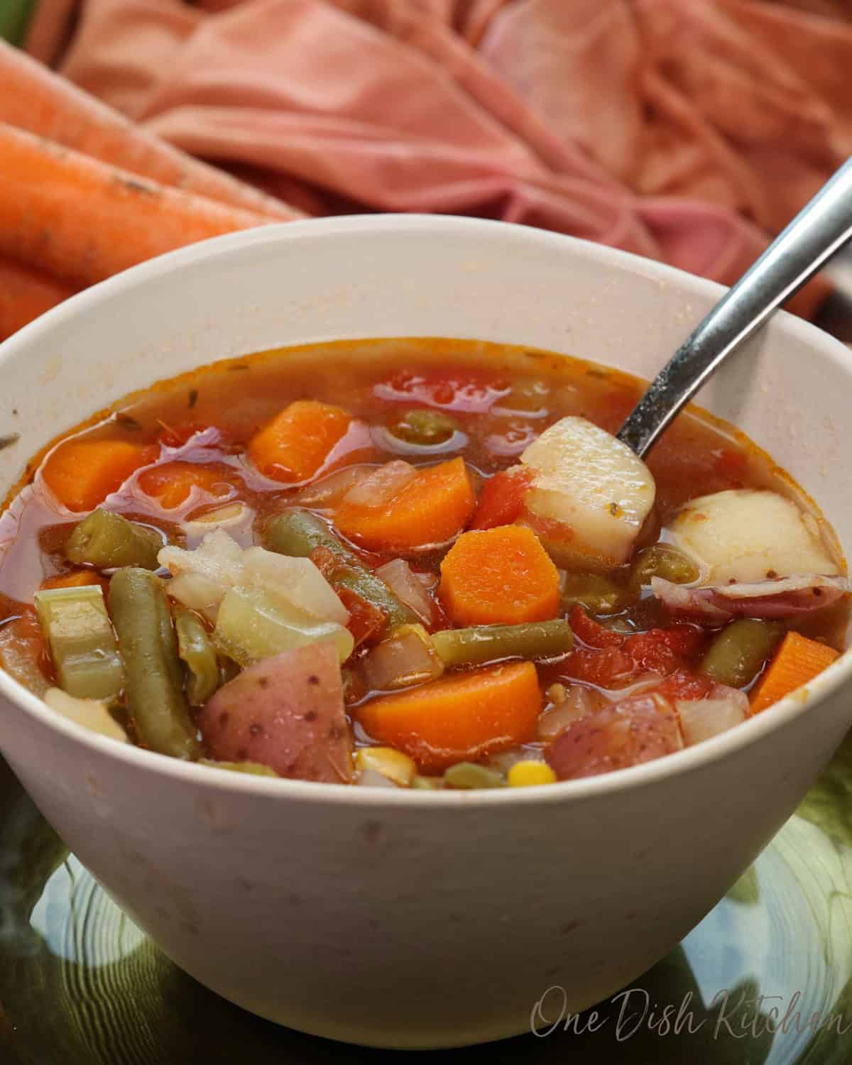 a bowl of vegetable soup on a silver tray.