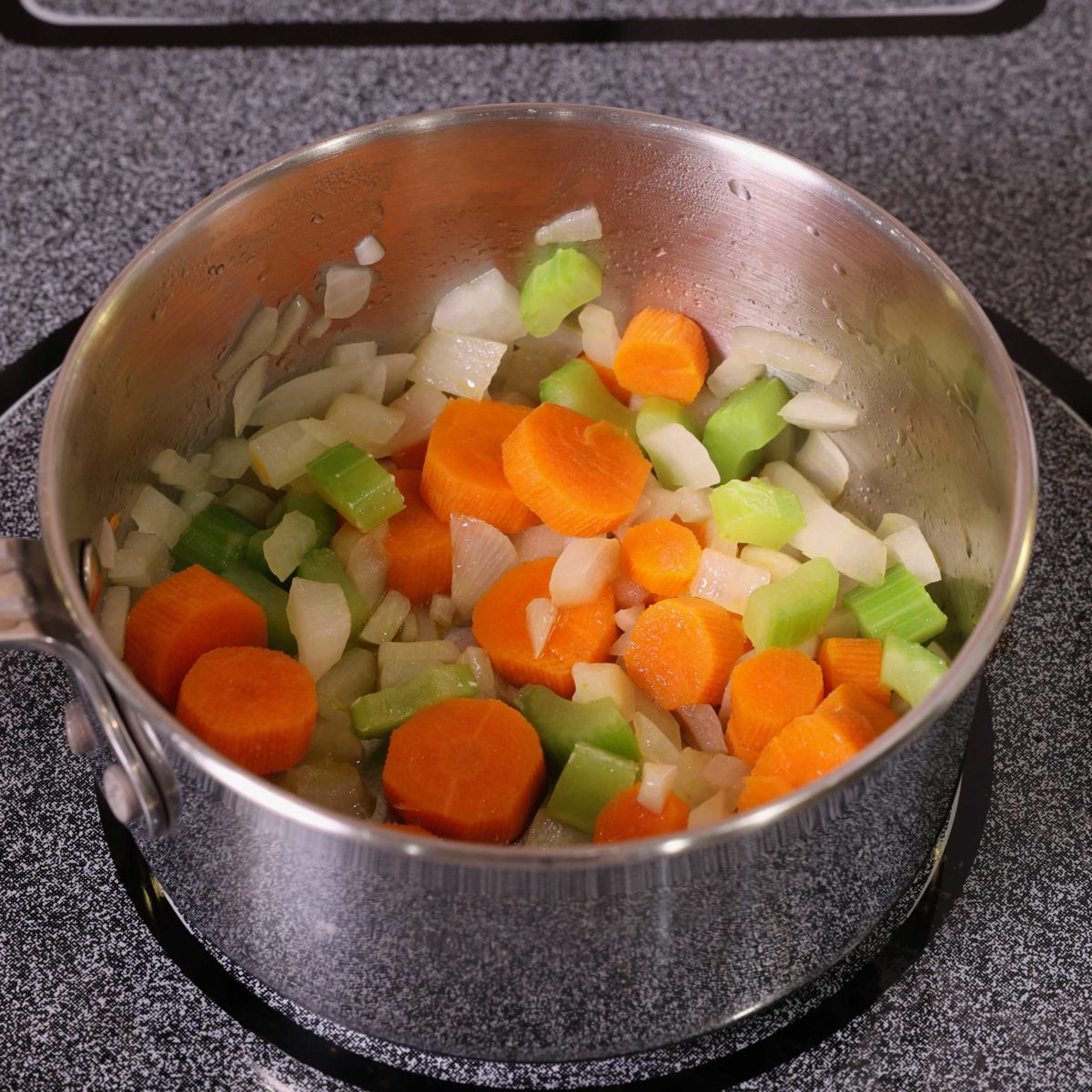 carrots, celery, onions, and garlic cooking in a small saucepan.