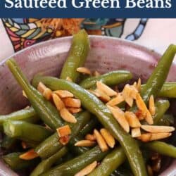 a pink bowl filled with green beans tossed with almonds.