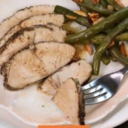 slices of turkey tenderloin on a white plate with a fork.