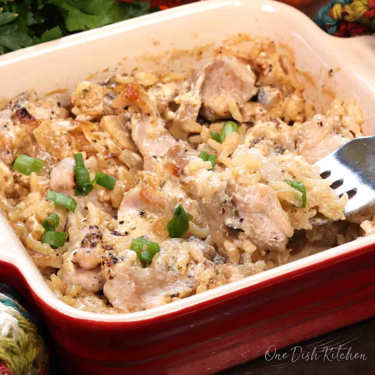 a small chicken and rice casserole in a mini red baking dish with a fork on the side.