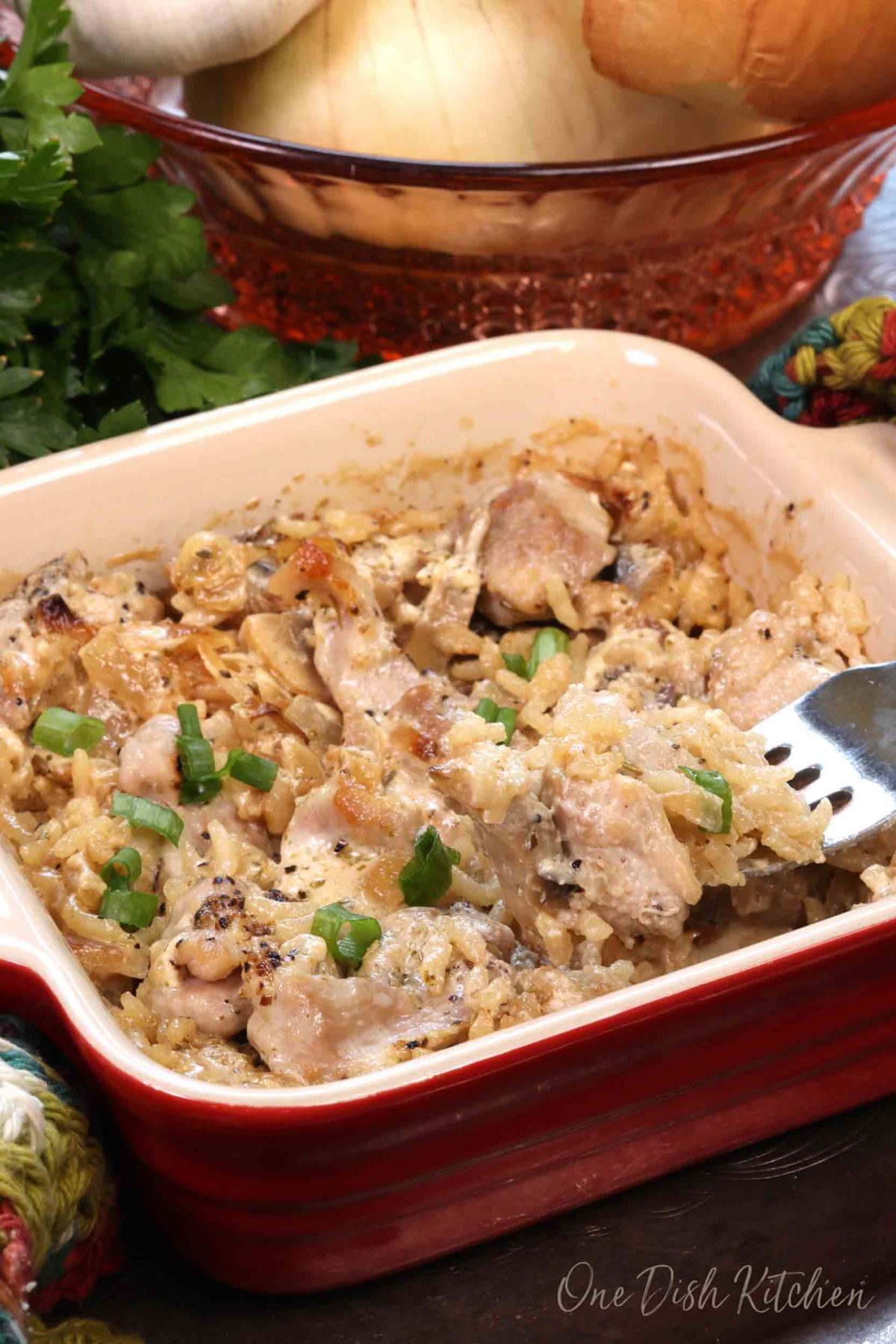 a fork filled with chicken and rice above a small casserole dish.