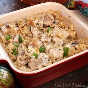 a mini chicken and rice casserole topped with chopped green peppers in a square red baking dish
