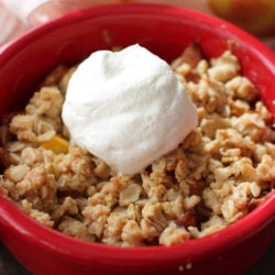 a peach crisp topped with a small amount of homemade whipped cream