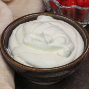 a small batch of homemade whipped cream in a purple bowl.