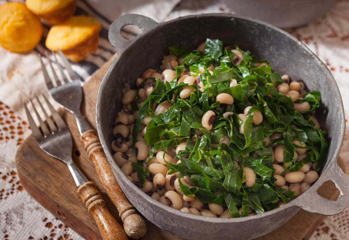 a bowl of black eyed peas  next to a fork and corn muffins.