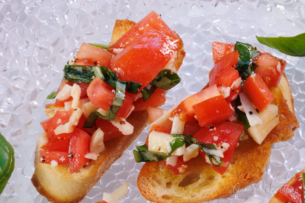 two pieces of tomato bruschetta on a plate.
