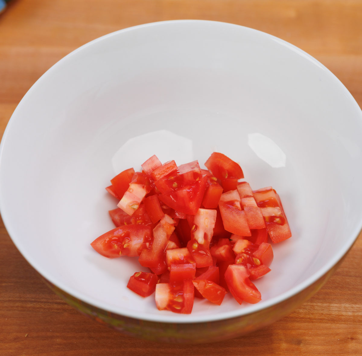 a white bowl filled with chopped tomatoes.