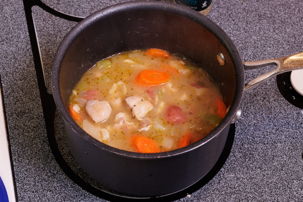 broth, vegetables, and chicken in a small pot.