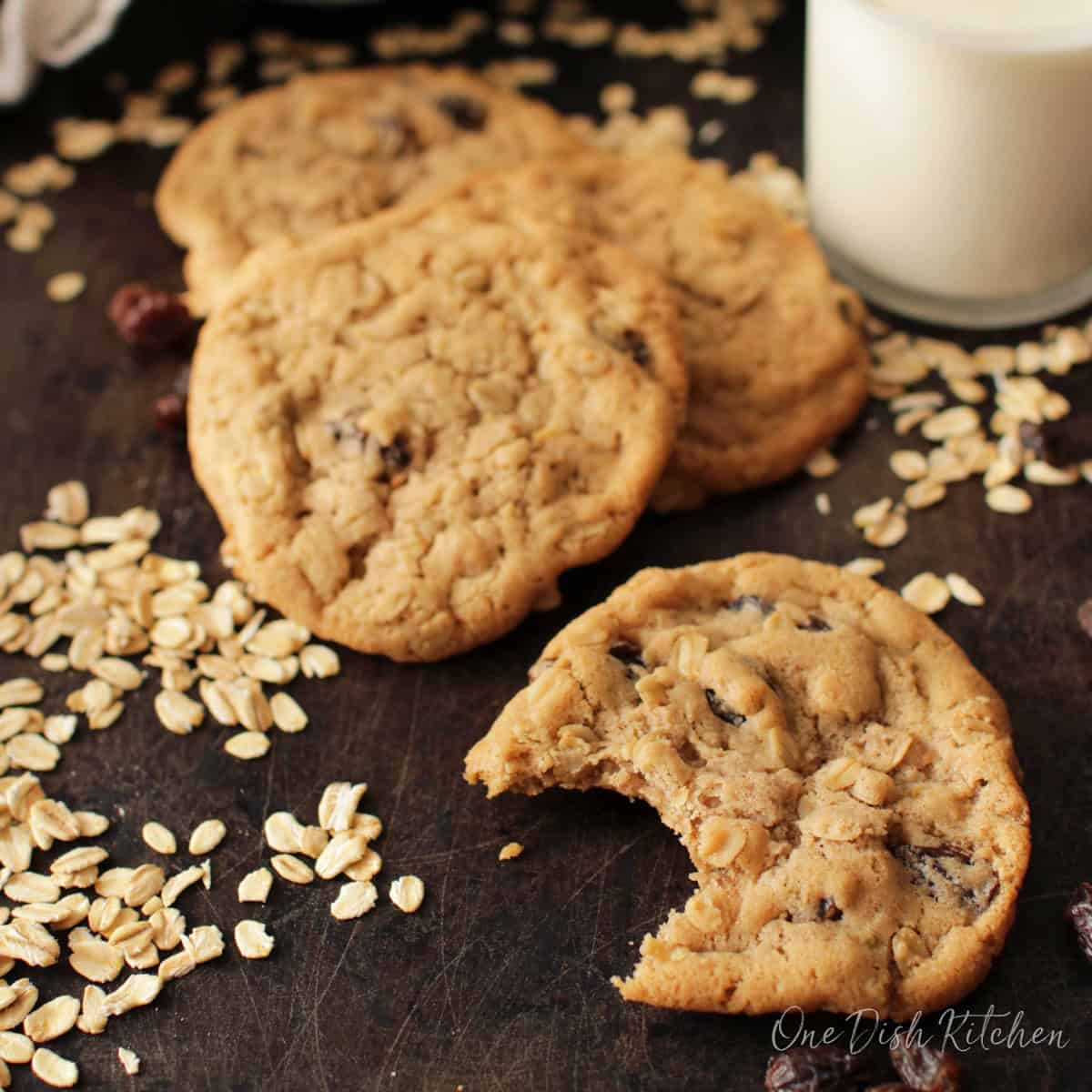 a small batch of oatmeal raisin cookies with old fashioned oats scattered around the plate.