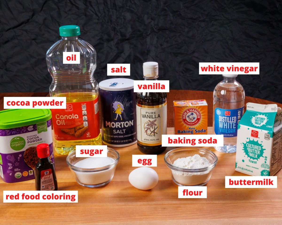 ingredients needed for red velvet cake on a wooden cutting board.