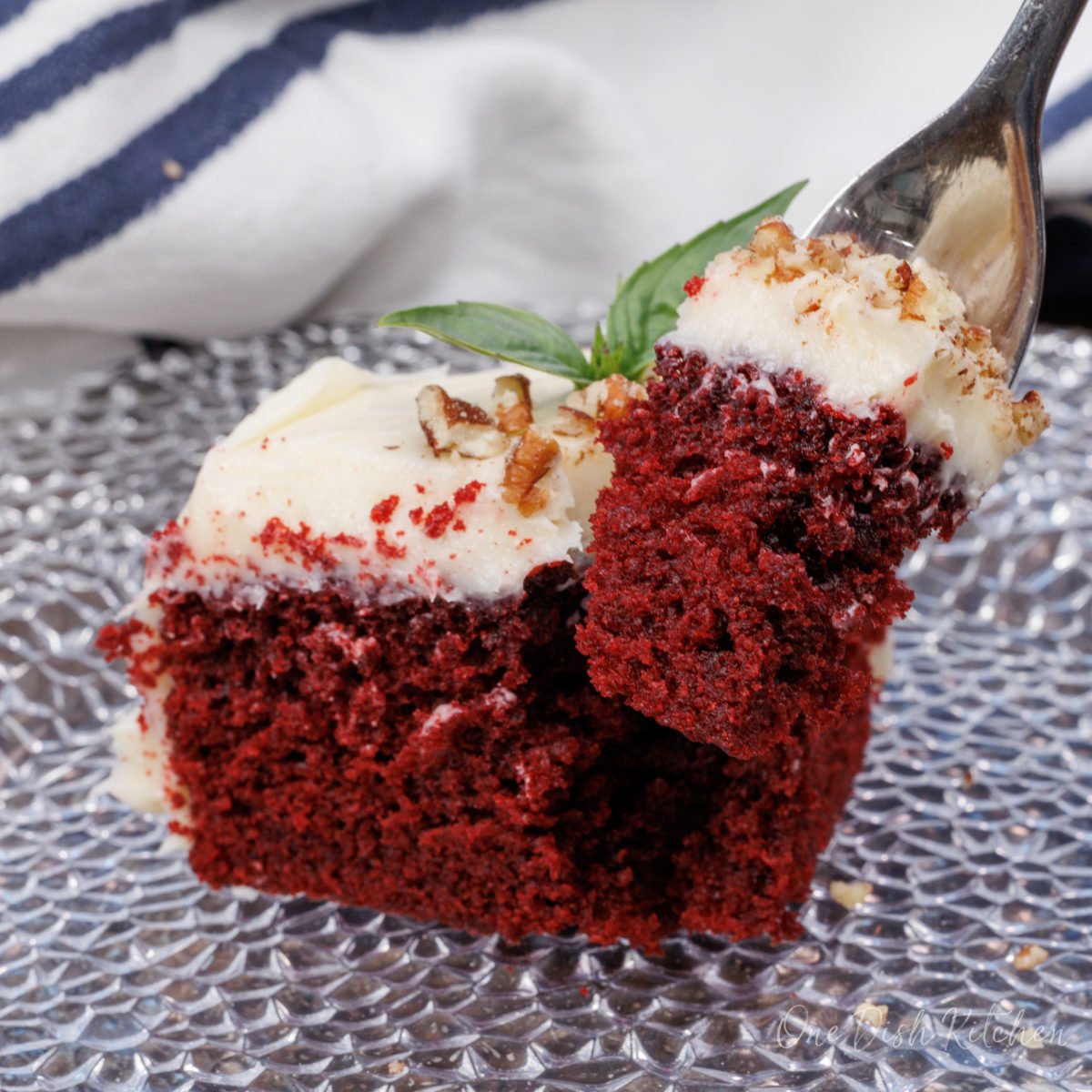 a forkful of red velvet cake next to a slice of cake on a plate.