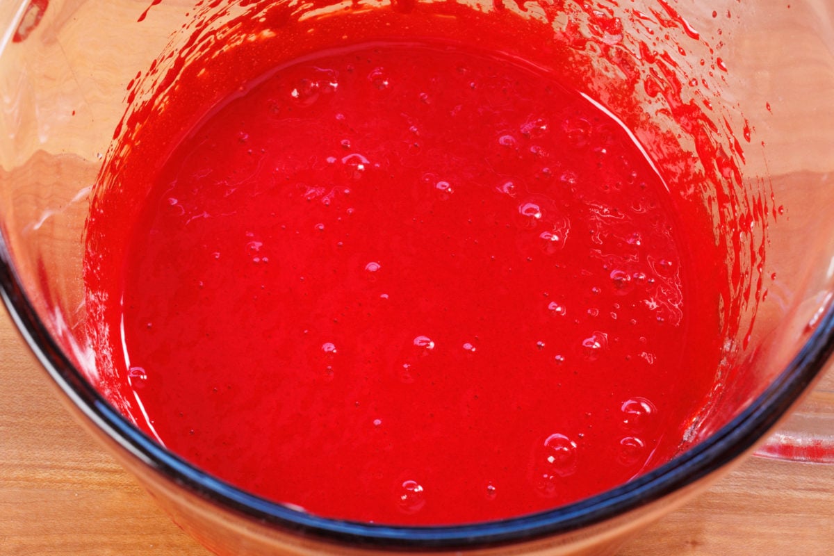 red food coloring, egg, oil, and sugar in a mixing bowl.