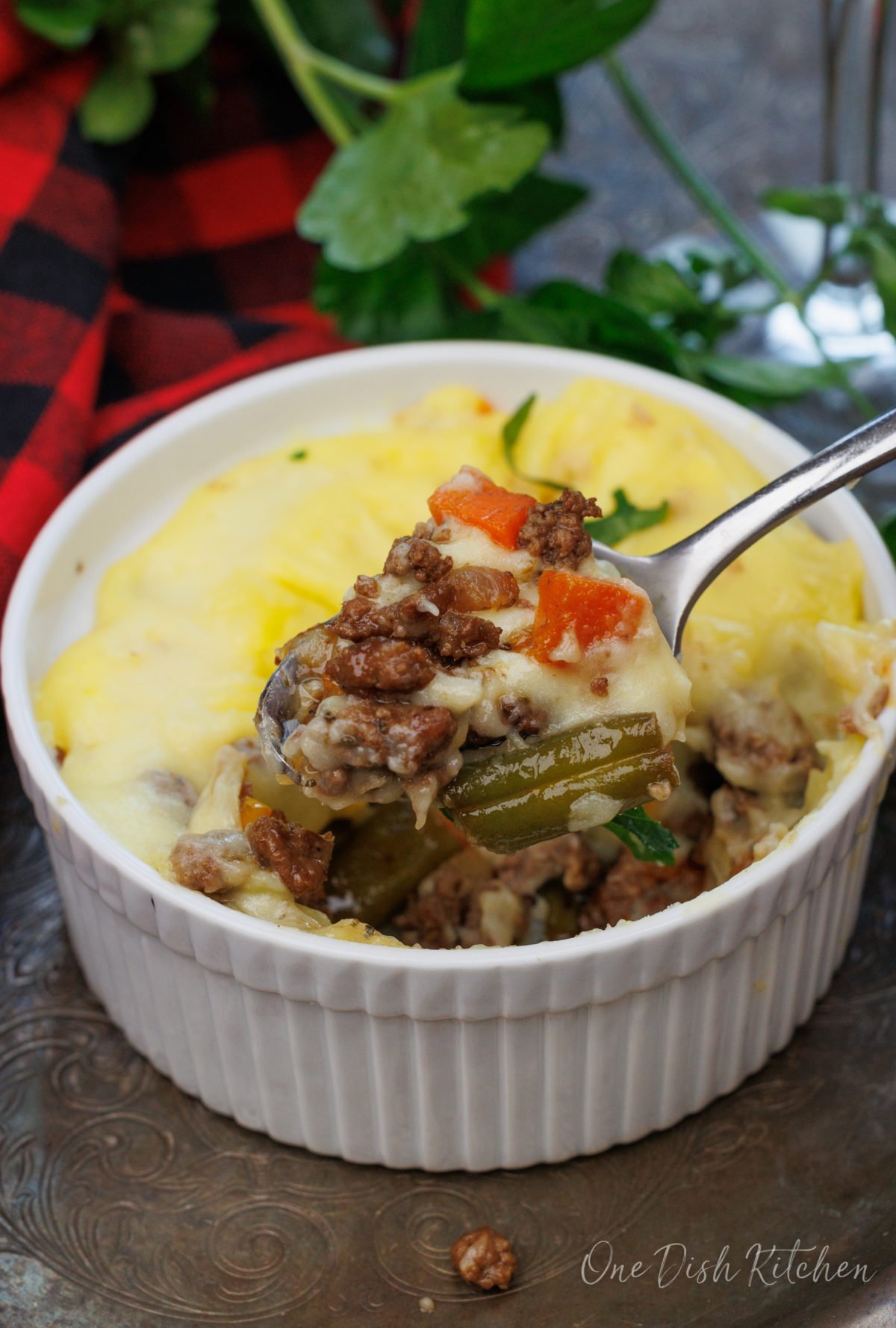 a mini shepherds pie in a small ramekin next to a glass of red wine.