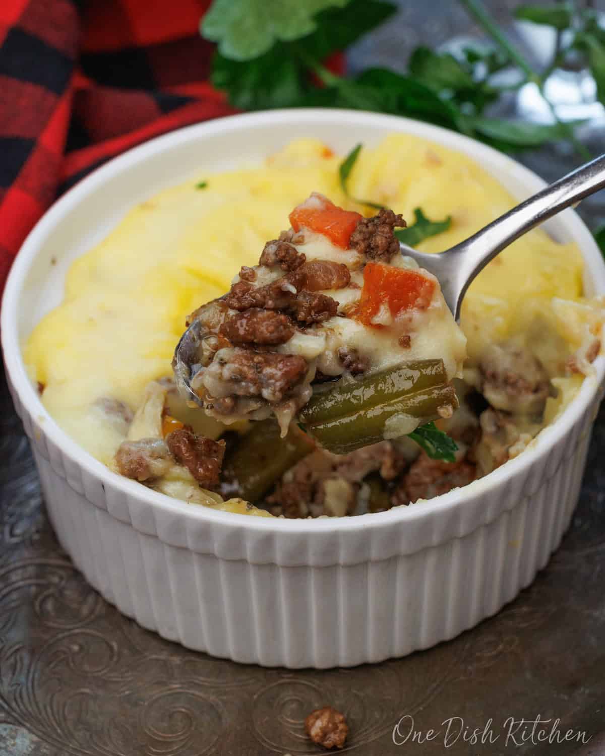 a mini shepherds pie in a small ramekin next to a glass of red wine.
