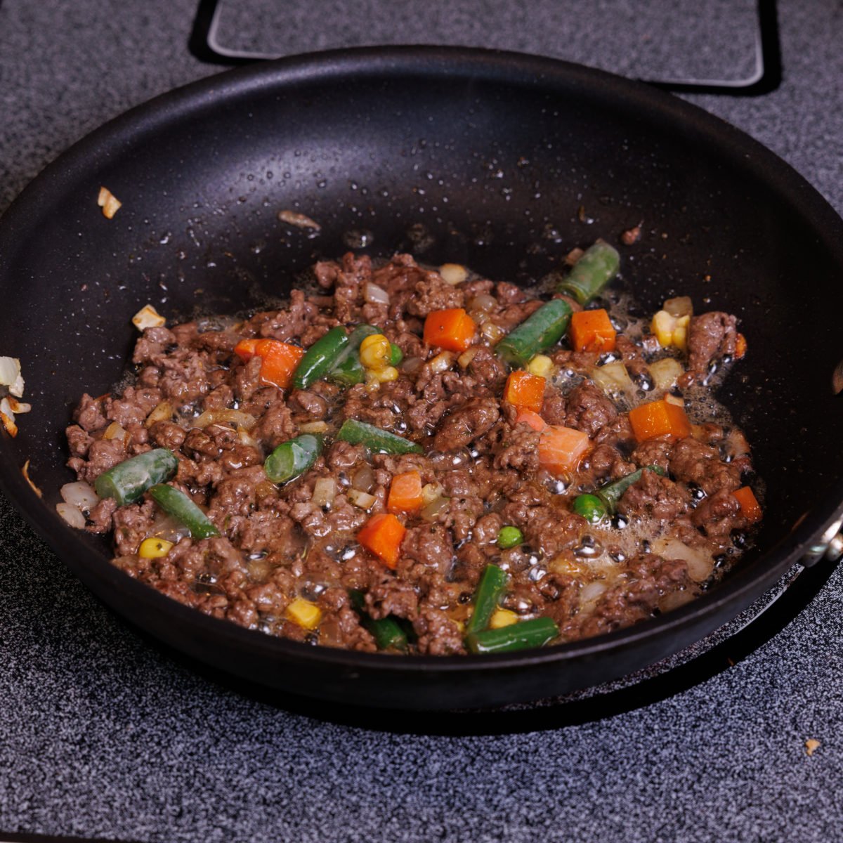 minced lamb and vegetables in a black skillet.
